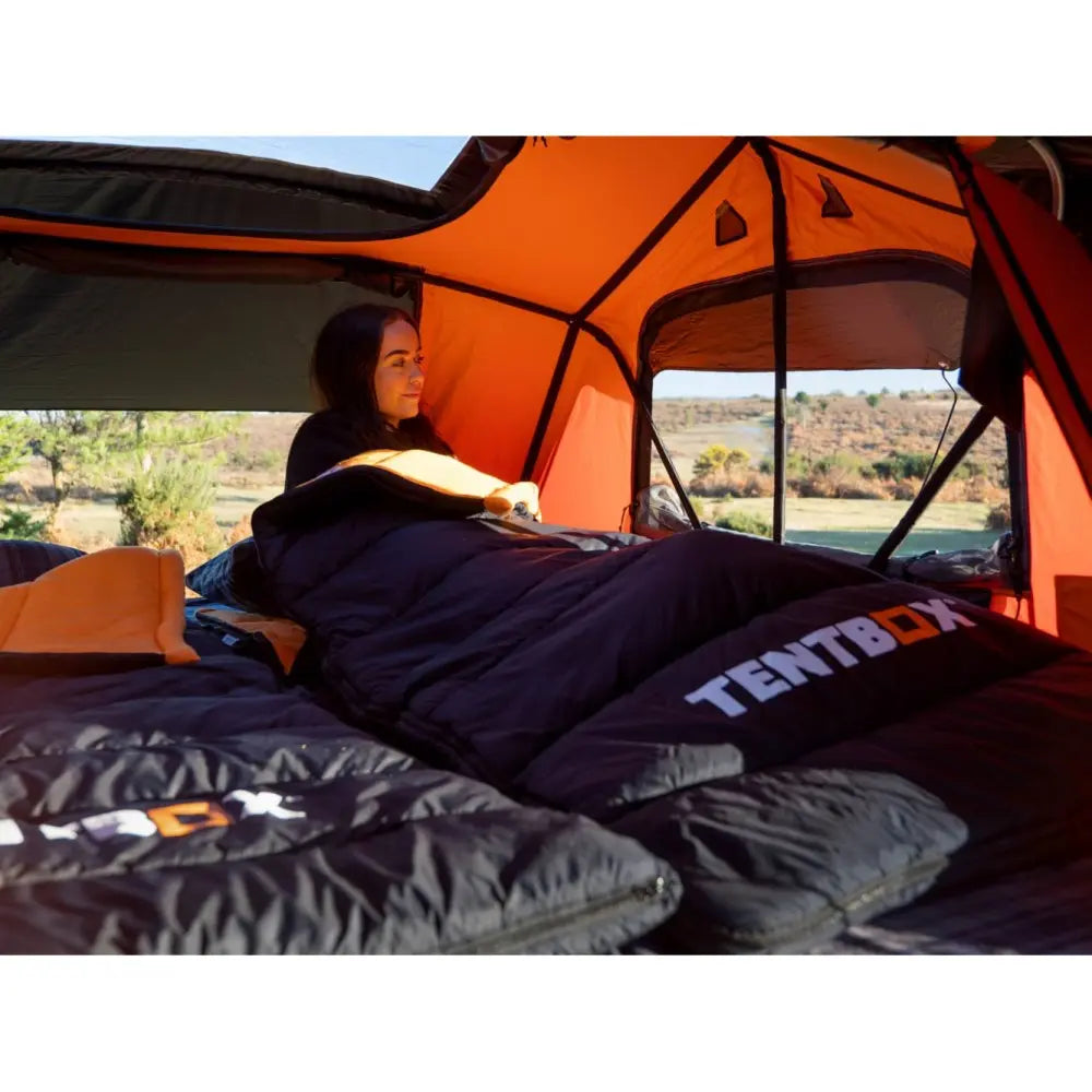 A woman using the TentBox Sleeping bag inside a TentBox Rooftop tent